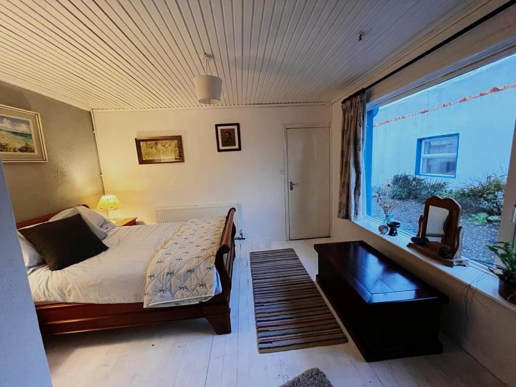 a bedroom with a bed and a large window at Tranquilty in Ballyheigue