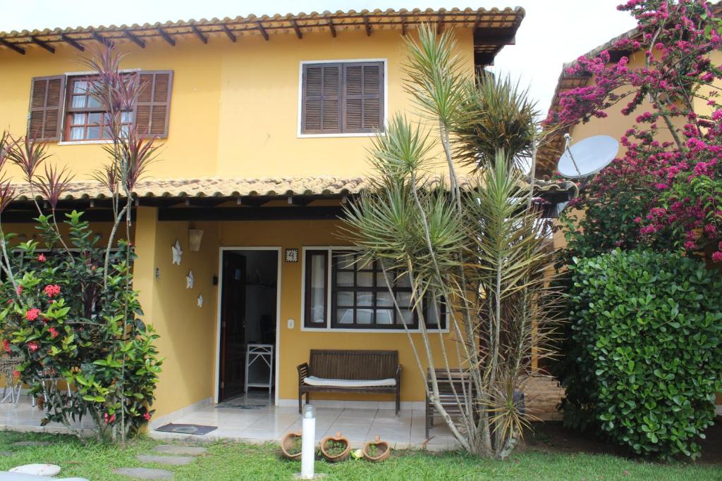 une maison jaune avec une chaise dans la cour dans l'établissement Casa em Búzios com Vista para o Mar, à Búzios