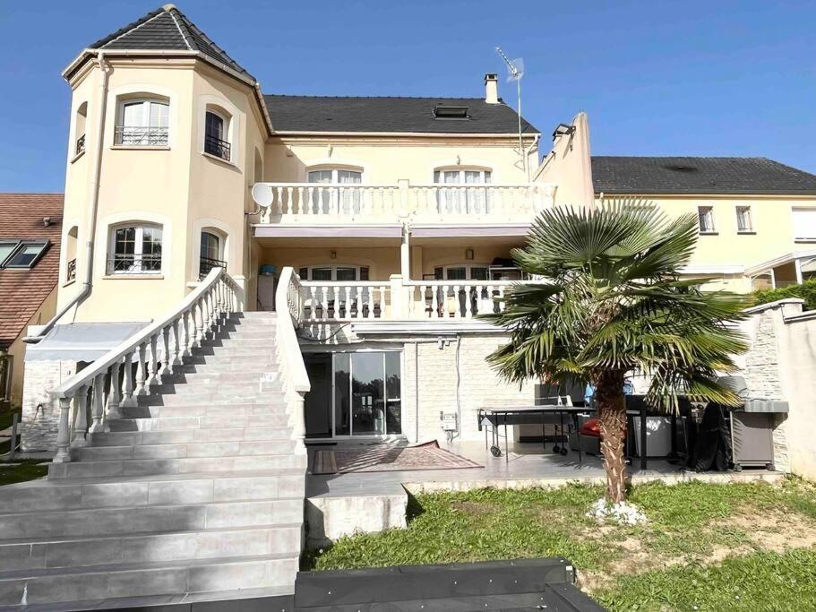 ein großes weißes Haus mit einer Palme davor in der Unterkunft Demeure - Haut Standing 11min Paris CDG in Dammartin-en-Goële
