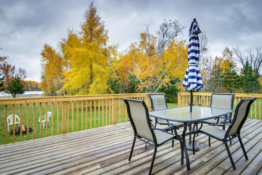 een tafel en stoelen op een terras met een paraplu bij Wright Retreat on Woodbury Lake Deck and Fire Pit! 