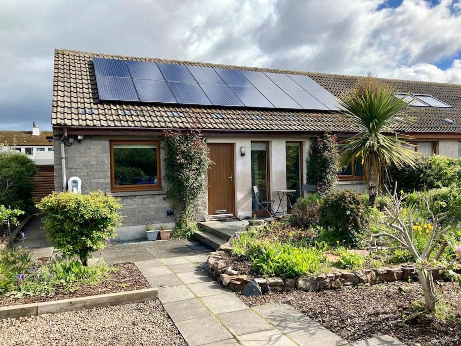 a house with solar panels on the roof at 3-Bedroom Eco-house with EV charger. in Rosemarkie