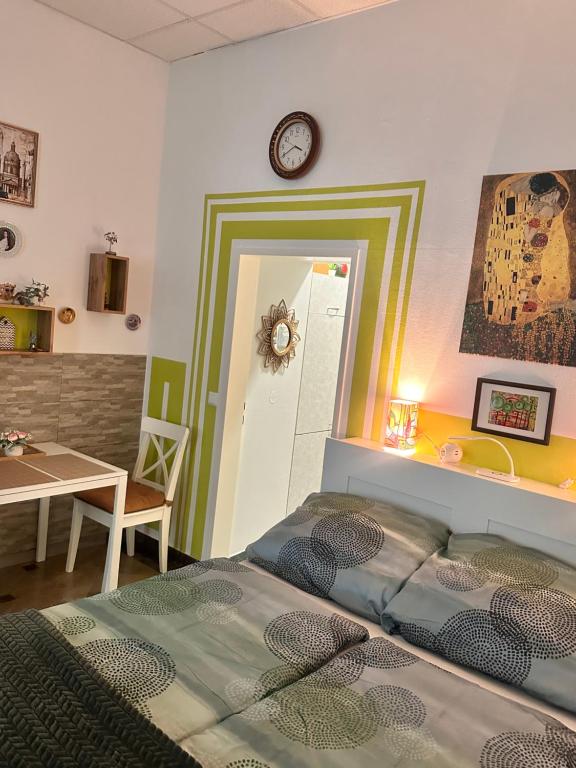 ein Schlafzimmer mit einem Bett und einem Tisch und einer Uhr an der Wand in der Unterkunft Centrally and green in Wien