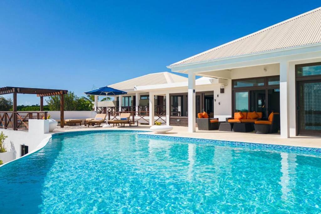 a swimming pool in front of a house at Songbird 4 BR Anguilla Villa in The Valley