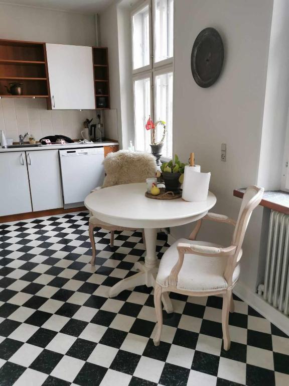 a kitchen with a table and chairs on a checkered floor at Big apartment on the town square in Faaborg