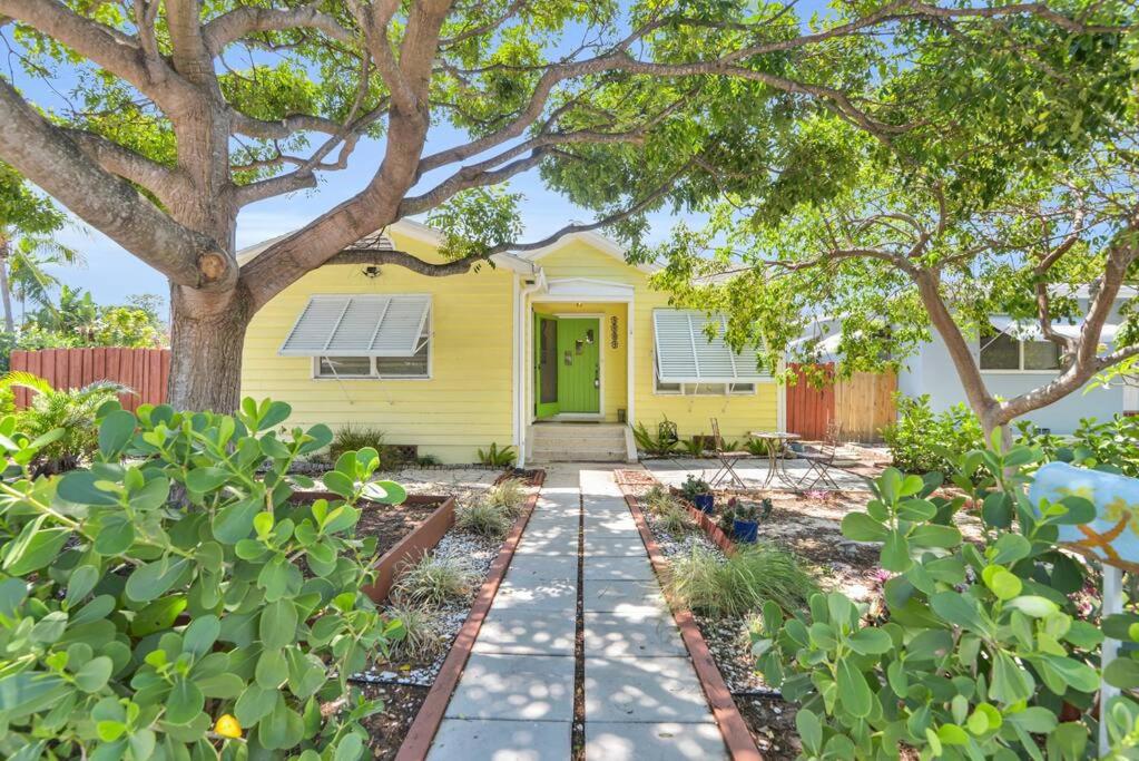 una casa amarilla con una puerta verde y árboles en Tranquility by the Beach, Sleeps 6, en Lake Worth