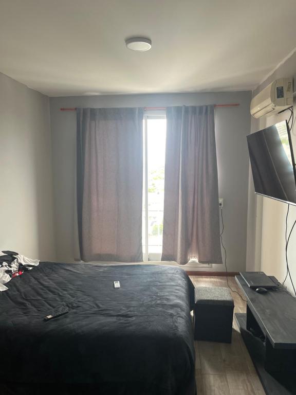 1 dormitorio con cama negra y ventana en Departamento con yacuzzi centrico en San Lorenzo