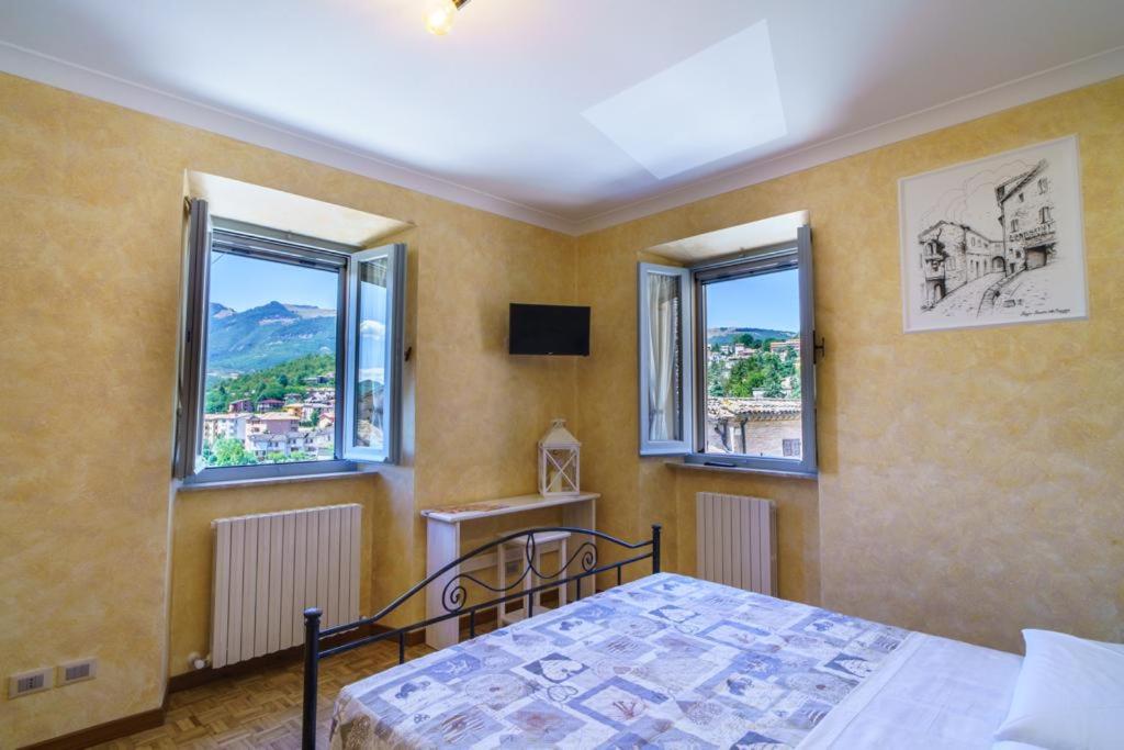 a bedroom with a bed and two windows at B&B La Locanda del Serafino in Sarnano