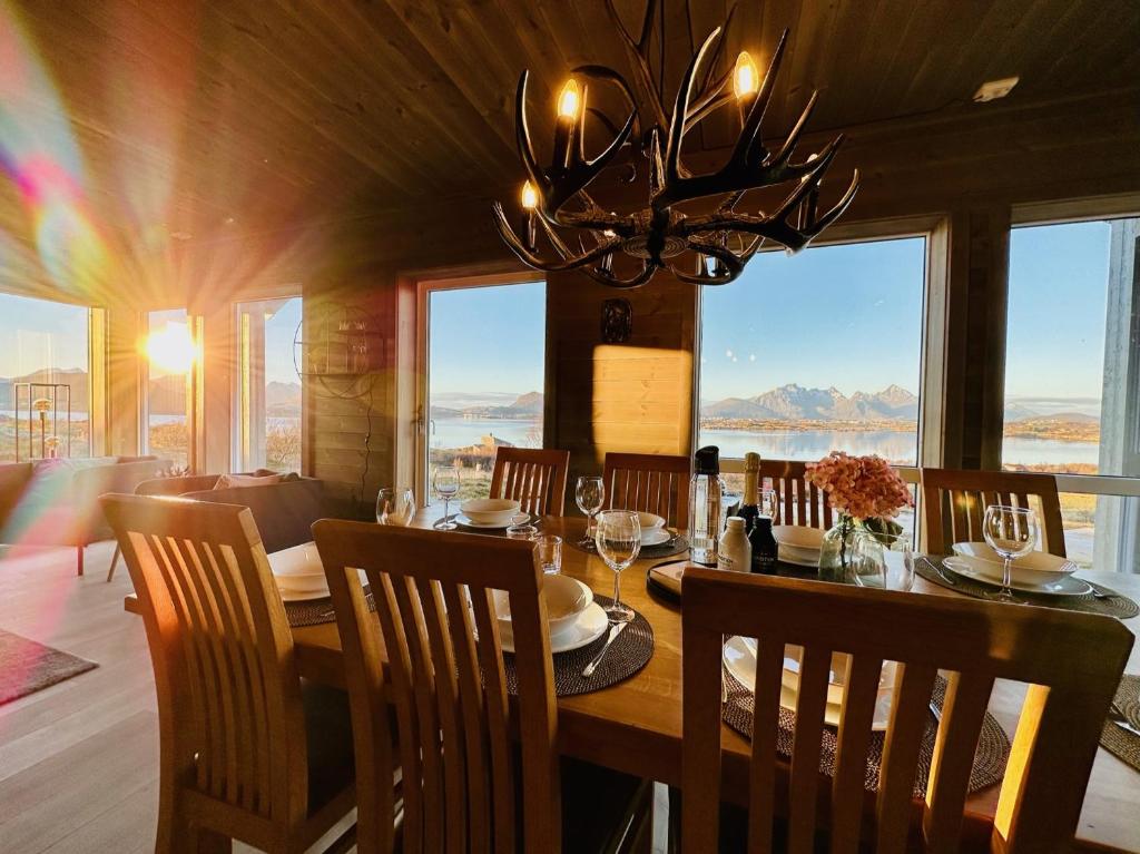 una sala da pranzo con tavolo, sedie e lampadario pendente di Lofotenholidays, Luxury cabin with panoramic view a Leknes