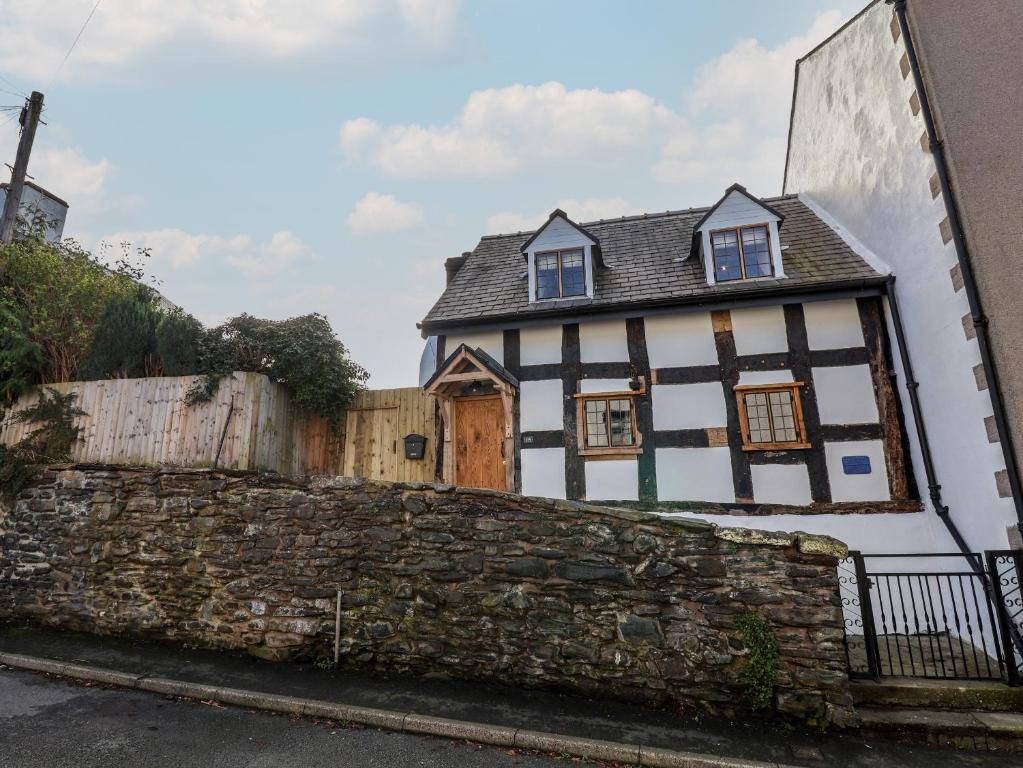 a white and black house with a stone wall at 18 Church Street in Llangollen