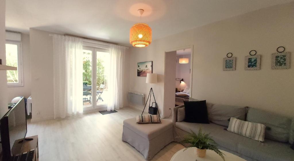 uma sala de estar com um sofá e uma mesa em Les Capitouls - avec entrée autonome, jardin & parking privé ! - em Toulouse