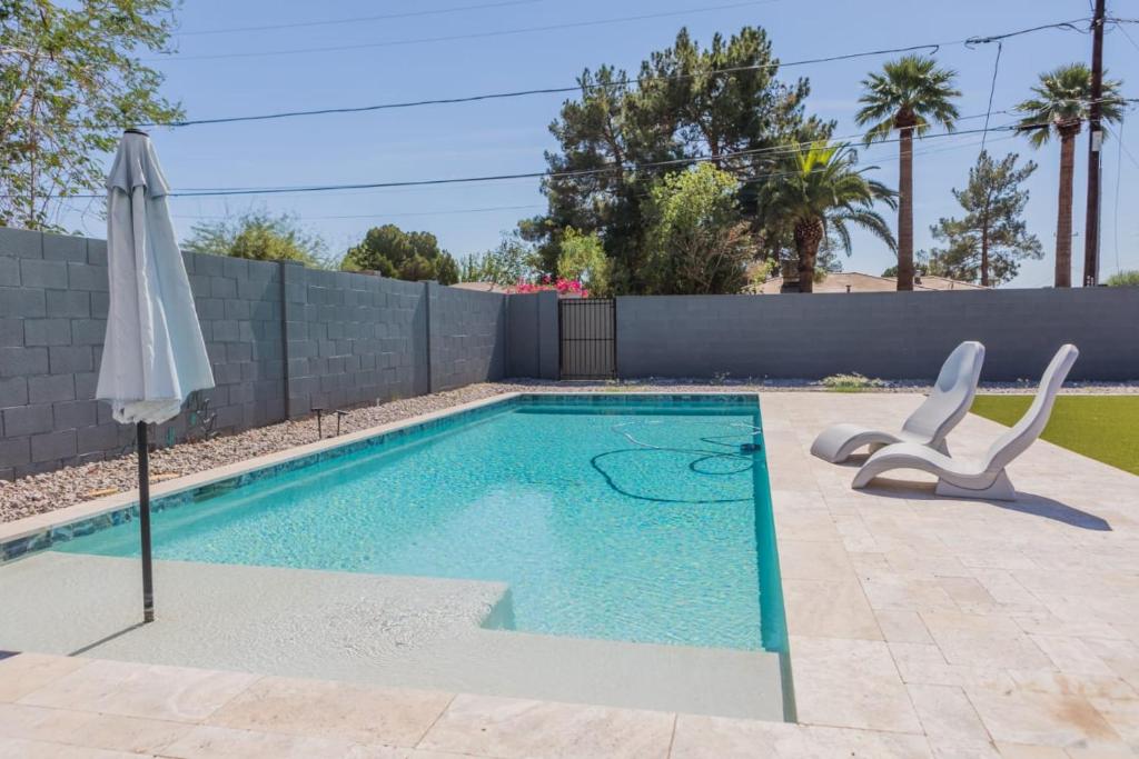 a swimming pool with two chairs and an umbrella at Modern Arcadia Lite Oasis Pool Heater BBQ in Phoenix
