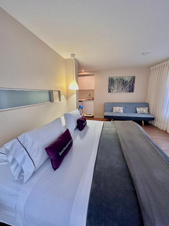 a large white bed in a room with a couch at Hotel Living 55 in Bogotá