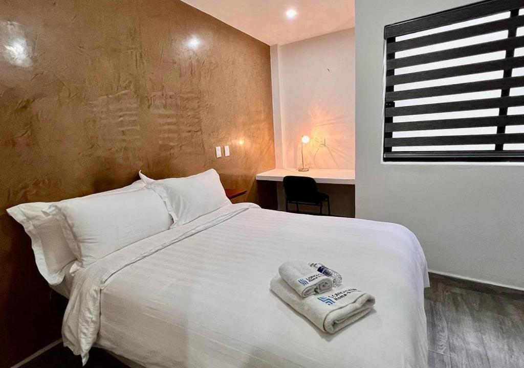 Un dormitorio con una cama blanca con toallas. en LONGVIEW HOME-STUDIOS, en Tepic