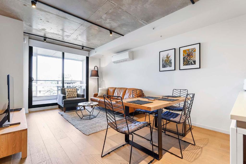 een woonkamer met een tafel en stoelen en een bank bij Modern Urban Retreat in Brunswick in Melbourne