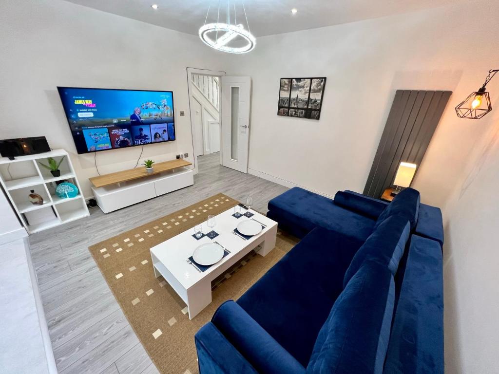 a living room with a blue couch and a tv at Wembley Stadium Luxury 6 bed sleeps 14 in London