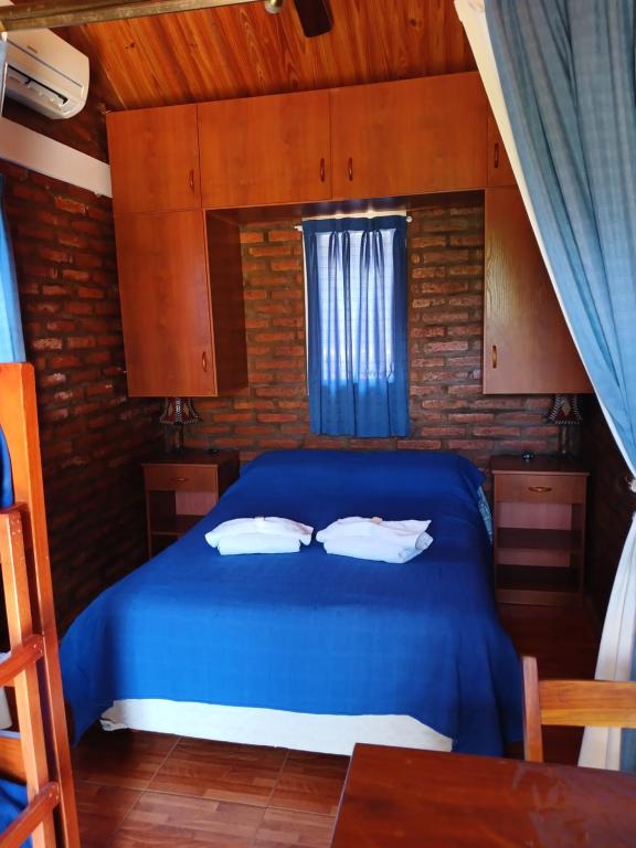 1 dormitorio con cama azul y ventana en Los olivos en Capilla del Monte