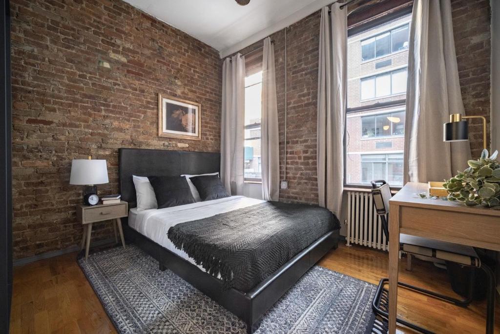 - une chambre avec un lit et un mur en briques dans l'établissement Apartment 253: Chelsea, à New York