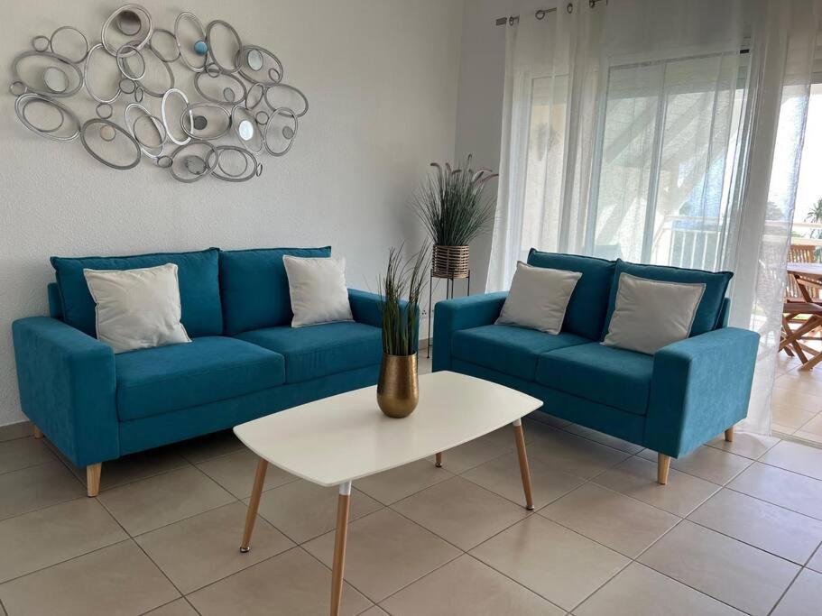 un sofá azul y una mesa en la sala de estar en KANOA LODGE piscine et vue mer, en Saint-Claude