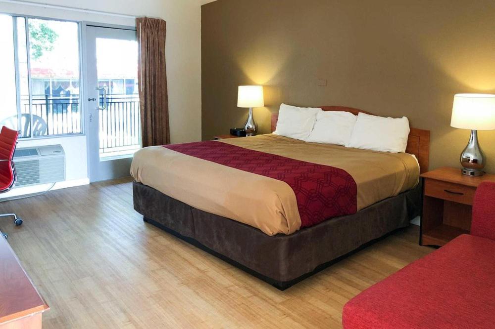 um quarto de hotel com uma cama e uma varanda em Garden Inn & Suites Oakland Airport em Oakland