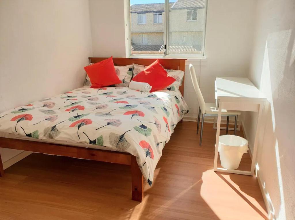 een slaapkamer met een bed met rode kussens en een raam bij Private Room in a 3-Bedroom Apartment-3 in Canberra