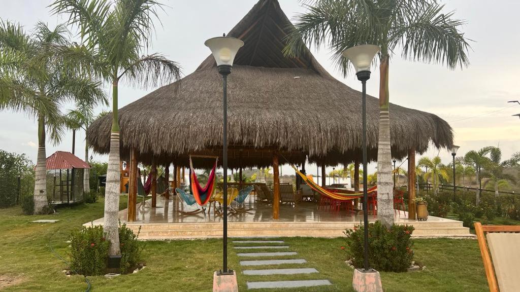 a pavilion with a straw roof with hammocks and palm trees at BRISAS DE BARU in Ararca