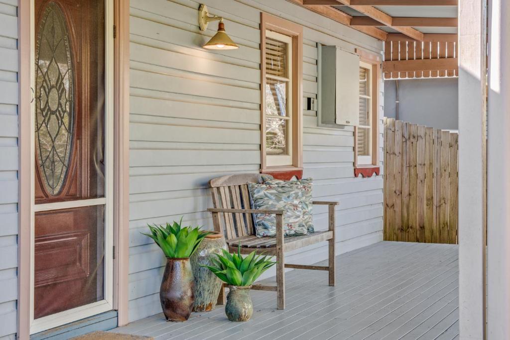 a porch with a rocking chair on a house at Whispering Pines Cottages in Wentworth Falls