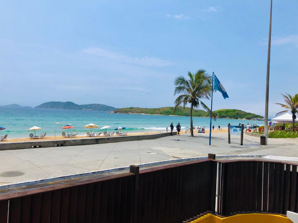 a beach with chairs and umbrellas and the ocean at Flat Pé na Areia Cabo Frio in Cabo Frio