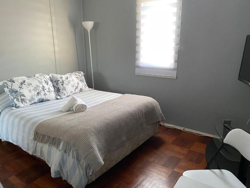 um quarto com uma cama, uma janela e um candeeiro em Central y Tranquilo alojamiento em Villa Alemana
