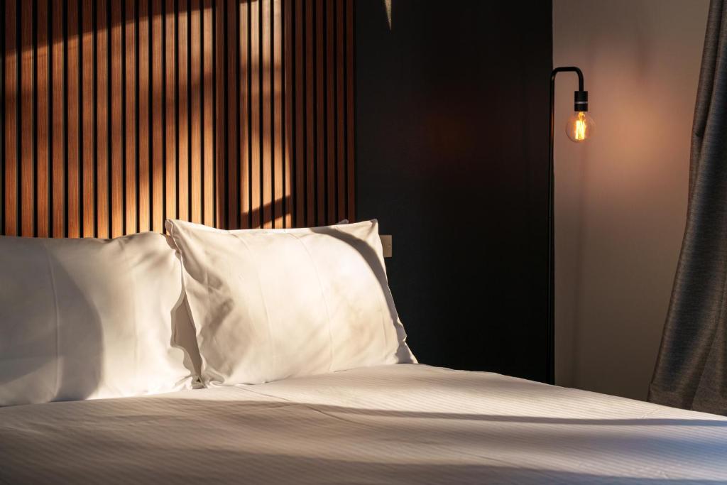 un letto con lenzuola e cuscini bianchi in una stanza di Echo Point Discovery Motel a Katoomba