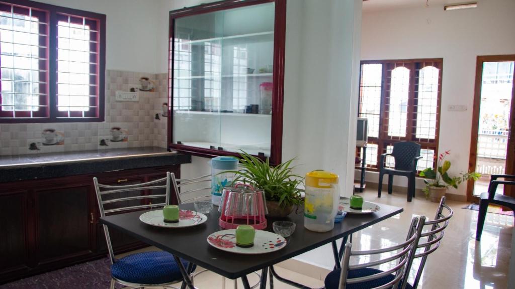 a dining room with a table with chairs and a kitchen at Spice Cottage Homestay in Thekkady