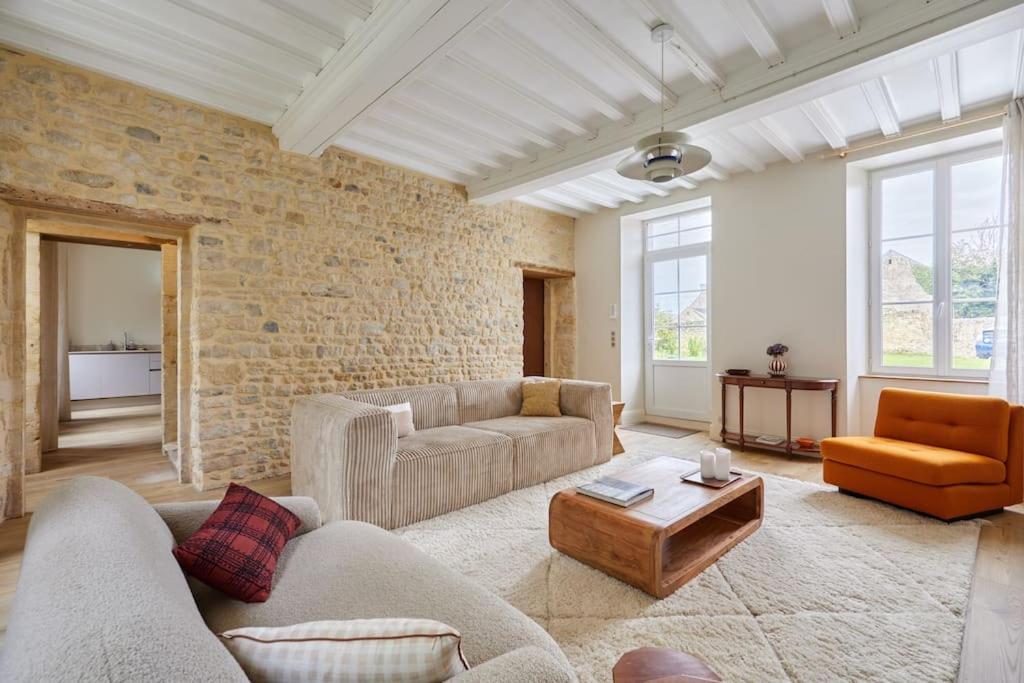 a living room with two couches and a brick wall at Maison Maliott in Colleville-sur-Mer