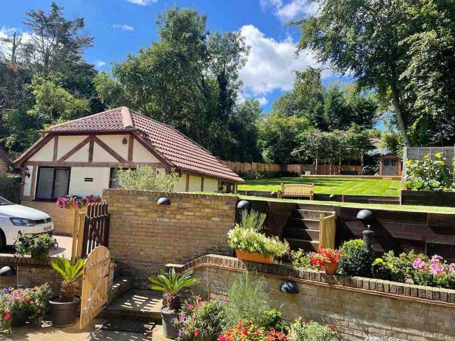 un jardín con una valla de ladrillo y flores en The Cosy Cottage, Old Soles bridge Lane, en Chorleywood