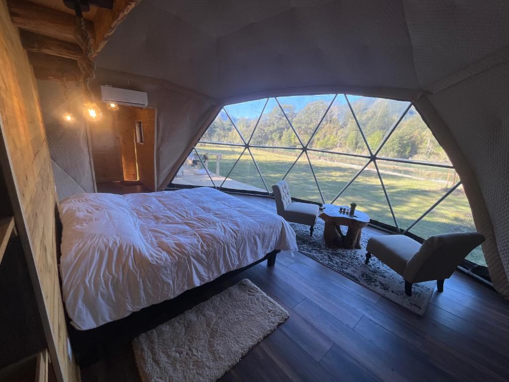 ein Schlafzimmer mit einem Bett und einem großen Fenster in der Unterkunft Alma Andina in Puelo