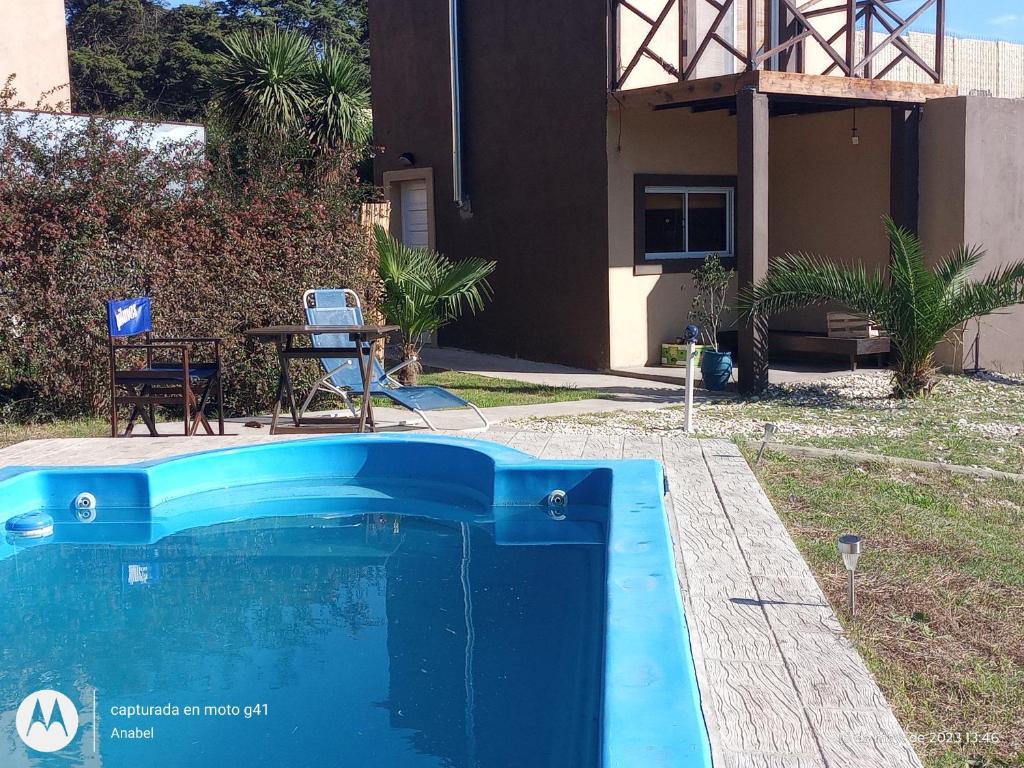 una piscina azul frente a una casa en Cabaña La Tamarita barrio colinas verdes Sierra de los Padres en Mar del Plata