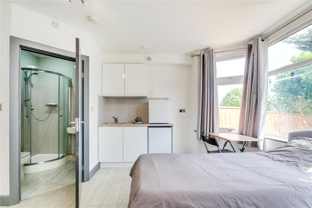 1 dormitorio con cama, ducha y mesa en Modern Designer Studio Flat London, en Londres