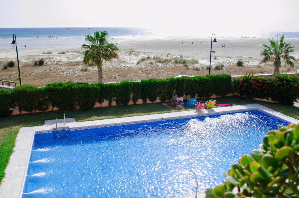 a large blue swimming pool next to a beach at Apartamento Los Lances II in Tarifa