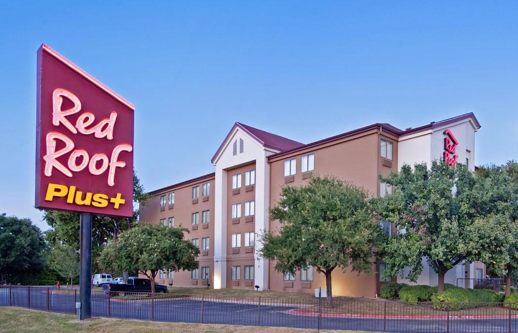 a red roof plus sign in front of a building at Red Roof Inn PLUS+ Austin South in Austin