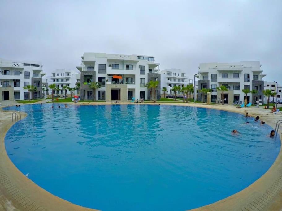 a large swimming pool in front of some apartment buildings at Appartement de luxe ,piscine,parking,Terrasse in Agadir
