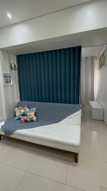 a bedroom with a large bed with a blue curtain at Biquinha - Praça 22 de Janeiro in São Vicente