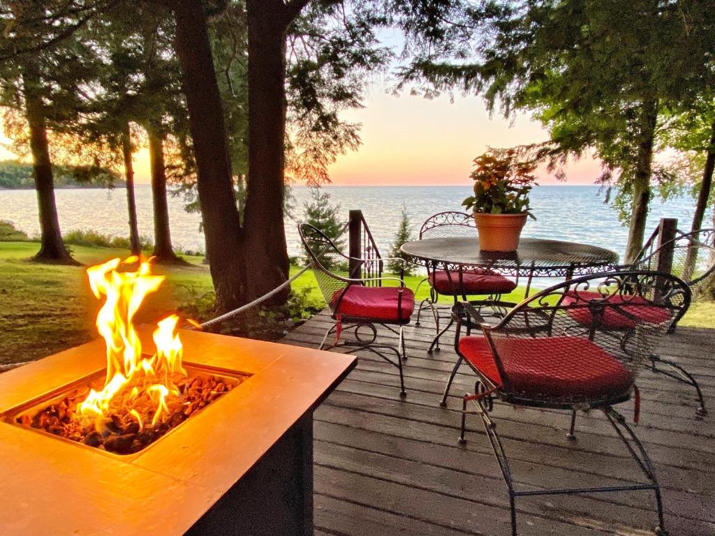 een vuurplaats op een terras met een tafel en stoelen bij Pine Cottage On Secret Cove in Sodus