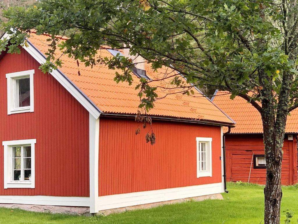 a red building with a tree in front of it at Holiday home Björklinge in Björklinge