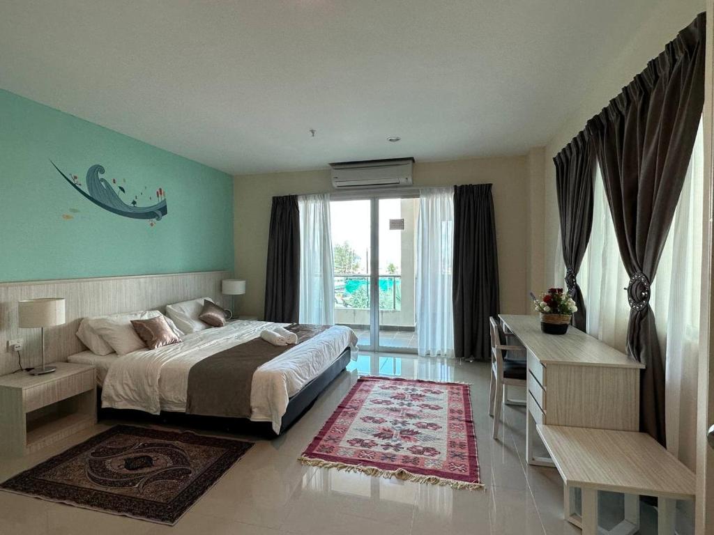 a bedroom with a bed and a desk and a window at Laguna Raudhah Apartment in Lumut