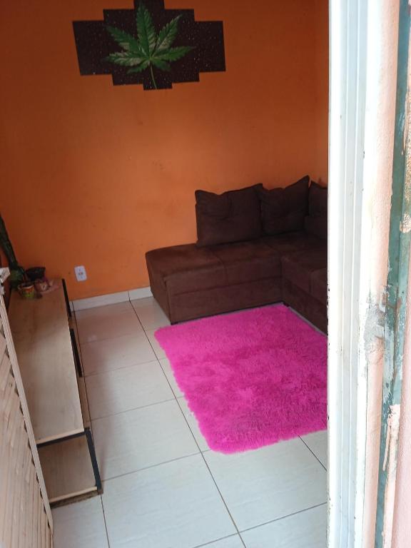 a living room with a couch and a pink rug at Conforto in Alto Paraíso de Goiás