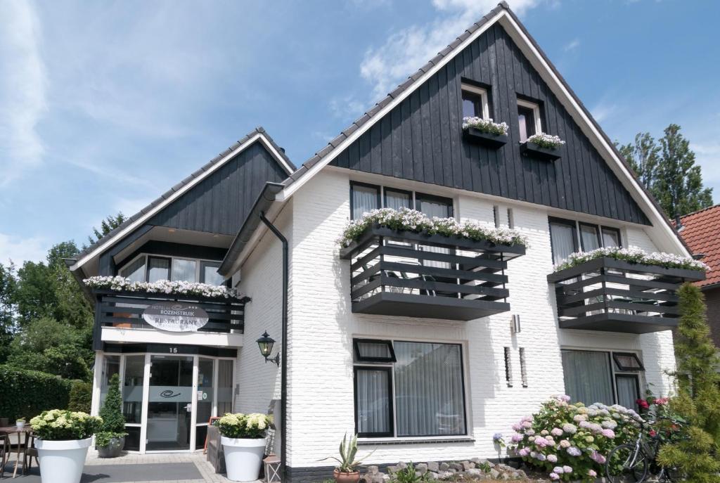 a white house with black roof and potted plants at De Rozenstruik in Ootmarsum