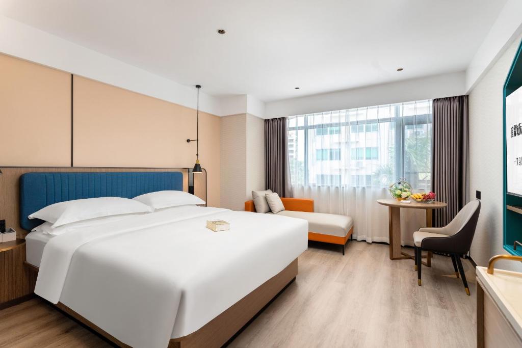 Habitación de hotel con cama blanca grande y escritorio. en Guangzhou Yilin Hotel, en Guangzhou