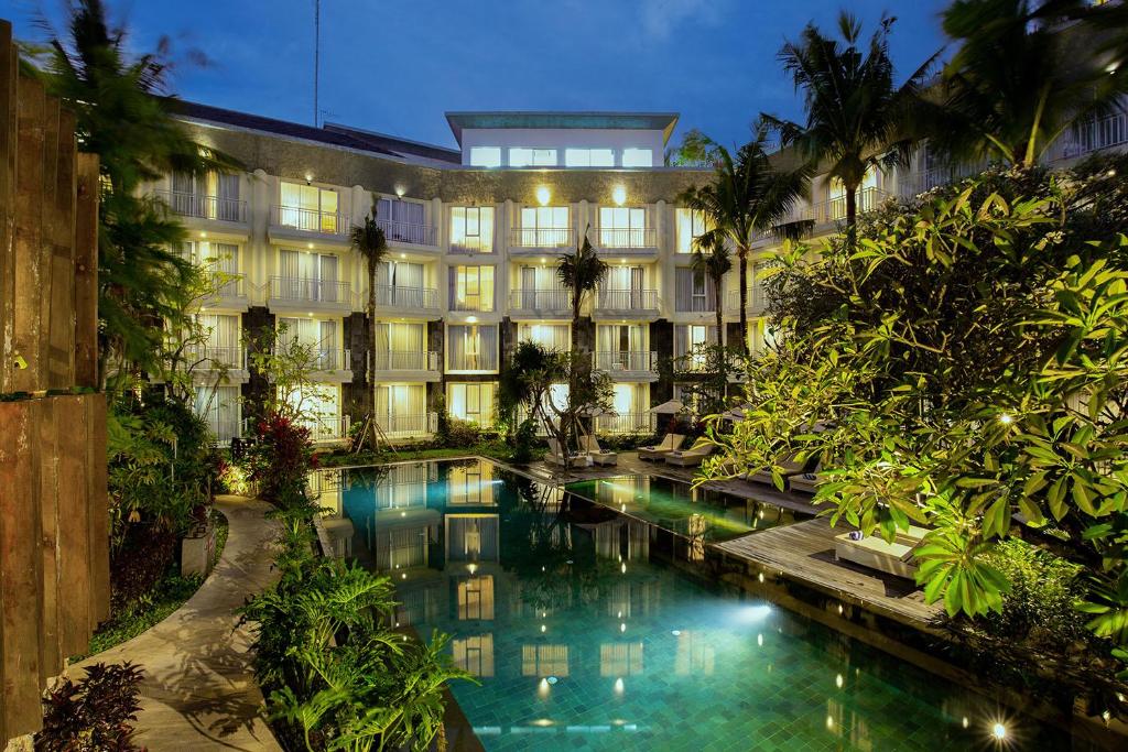 a hotel with a pool in front of a building at THE 1O1 Bali Fontana Seminyak in Legian