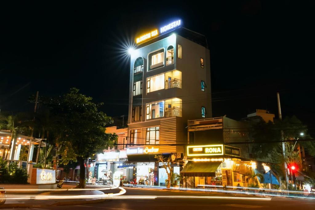 un palazzo alto con un cartello di notte di Blossom Sea Homestay Quy Nhơn a Quy Nhon