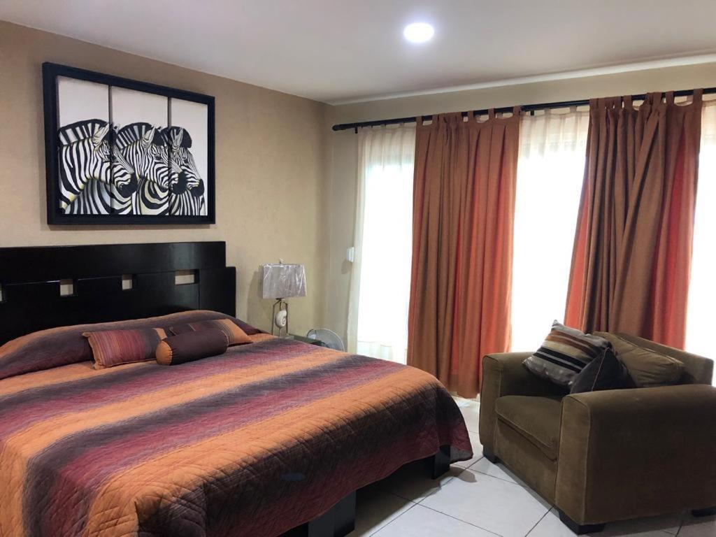 - une chambre avec un lit, une chaise et des fenêtres dans l'établissement Amplio departamento en Marina, à Mazatlán