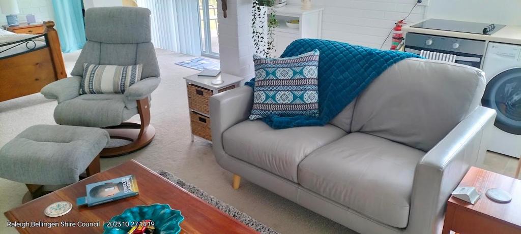 a living room with a couch and a chair at The Glade, peace among the trees on the river in Urunga