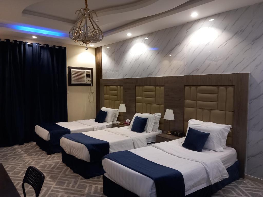 a hotel room with three beds with blue pillows at لانا العلا شقق مفروشة Lana Alula in AlUla